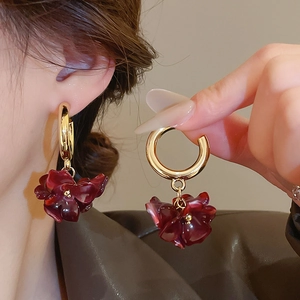 Detailed close-up of dark red flower drop earrings with golden hoops on model