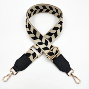 Detail of adjustable bag strap with black and beige arrow pattern and gold metal hooks