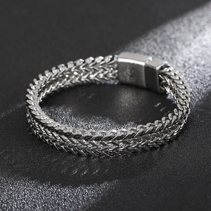 Detail of silver double row wheat chain bracelet with square magnetic buckle on black background