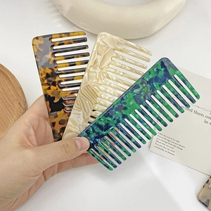 Three acetate hair combs with vintage marble patterns and shell finish in hand