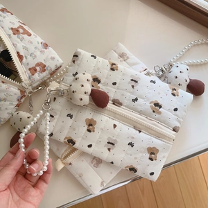 Close-up of quilted bear print pouch with pearl strap and mushroom charm detail