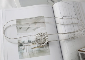 Close-up of silver ball chain belt featuring a round buckle with white pearl accents