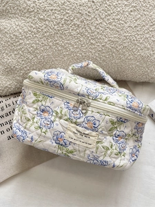 Quilted blue floral makeup bag with top handle and double zipper for travel storage
