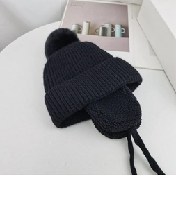 Detailed view of black knit winter hat with ear flaps and soft fleece lining