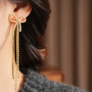 Model wearing 18k gold plated bow earrings with long sparkling zircon tassels