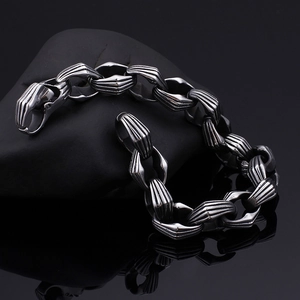 Dettaglio del bracciale punk in acciaio argentato su roccia nera con luci professionali