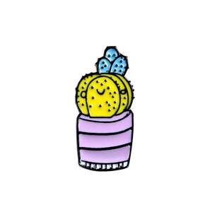 Close-up of colorful cartoon cactus enamel pins in yellow blue and pink colors