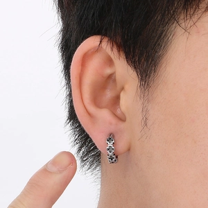 Close-up of vintage silver cross earring shown on ear for realistic size and texture
