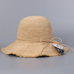 Detailed texture of handmade raffia sun hat featuring fringe brim and thin string bow
