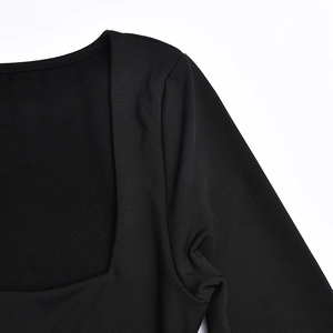 Detail des quadratischen Ausschnitts und der Stricktextur am schwarzen Langarmkleid