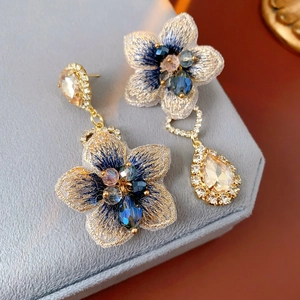 Vue macro de boucles d'oreilles vintage asymétriques avec fleurs brodées et cristaux