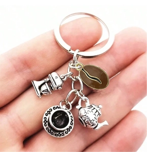 Detailed view of hand-held silver alloy keychain with coffee grinder and teapot charms