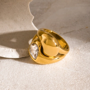 Dettaglio di un anello dorato massiccio con una grande gemma tonda chiara su pietra
