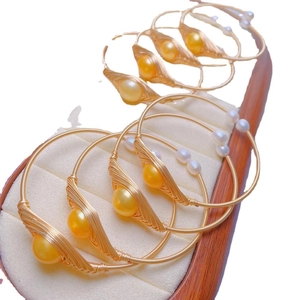 Elegant gold wire-wrapped bracelet featuring large golden pearl and small white pearl accents