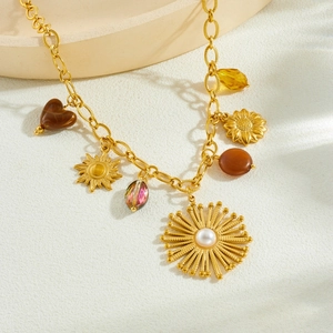 Collier vintage doré avec pendentif tournesol, perles et breloques sur fond texturé