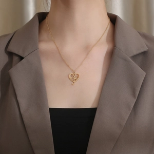 Close-up of a gold heart pendant with music notes on a stainless steel chain necklace