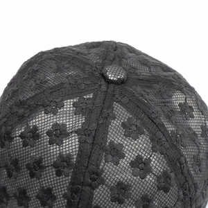 Top detail of black lace baseball cap featuring embroidered floral mesh and fabric button