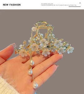 Close-up of golden hair claw with white flowers and dangling pearl tassels