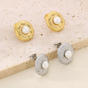 Detailed macro of gold and silver rope textured earrings featuring elegant white pearls