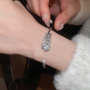 Close-up of a silver feather bangle with cubic zirconia on a wrist with white fur