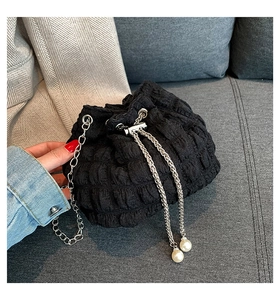Detail of black pleated fabric bucket bag with silver chain and large pearl accents