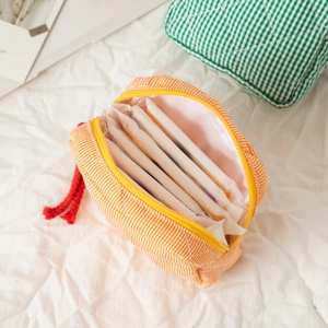 Close-up of quilted cotton sanitary bag with orange stripes and yellow zipper closure
