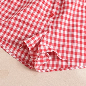 Detail of red and white plaid shorts featuring fabric texture and a matching red button