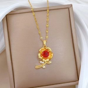 Macro shot of rose-shaped gold necklace with a red gem and diamonds on silk