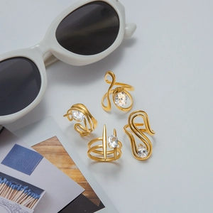 Detail of four 18K gold-plated titanium steel rings with cubic zirconia and wavy lines