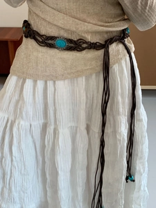 Detailed shot of bohemian waist chain with turquoise stone and woven tassel accents