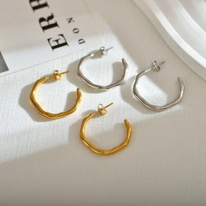 Close-up detail of irregular wave texture on gold and silver C-shaped hoop earrings