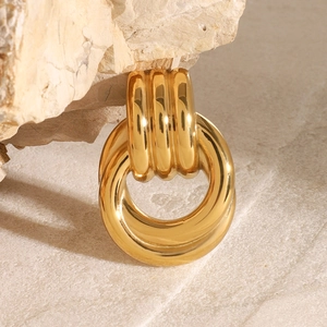 Detail of interlocking chunky golden geometric brooch on a textured sandstone block