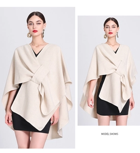 Detail of beige knit poncho shawl with front knot design over a black dress