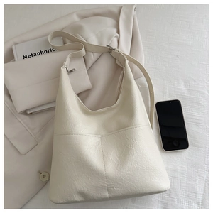 Detailed view of cream white tote bag with pleated texture on beige blazer background