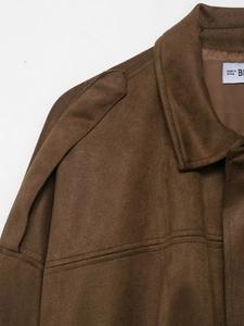 Détail de la veste bomber en daim marron avec pattes d'épaule et coutures précises