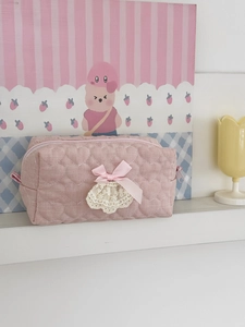 Detail of pink quilted makeup bag with heart stitching, silk bow and lace trim decor