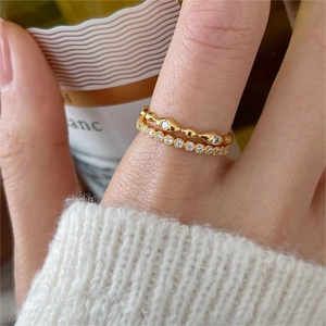 Elegant gold stacked 925 silver rings with wavy diamond design on woman's hand