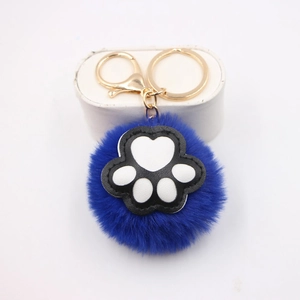 Detail of blue plush cat paw keychain with golden metal ring on white background