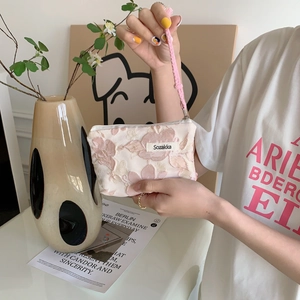 Minimalist floral lipstick bag with drawstring handle shown in a lifestyle hand-held pose