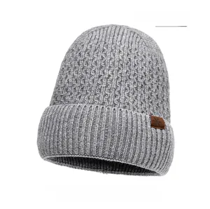 Detail view of light gray knit beanie featuring a brown leather snowflake patch