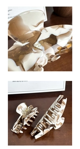Detail of brown and white marble acetate hair claws with gold glitter and logo