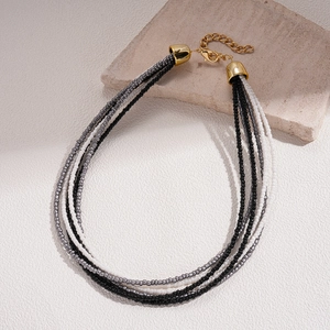 Detail of bohemian layered beaded necklace with black and silver glass beads and gold clasp