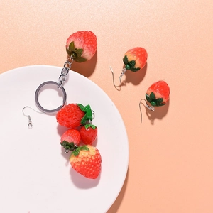 Realistic resin strawberry keychain and earrings set on a white plate with vibrant colors