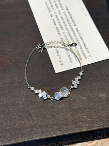 Macro detail of S925 silver bracelet with zircon flowers and milky white gemstone pendants