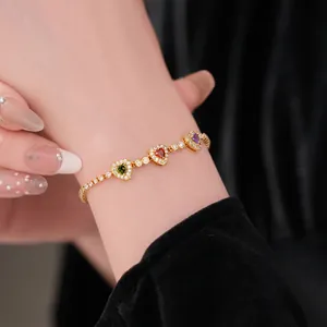 18k gold plated bracelet with emerald, ruby, and amethyst zircon heart charms on wrist