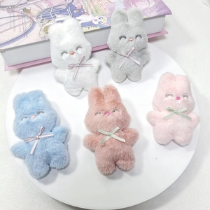 Détail de breloques lapins en peluche de cinq couleurs sur un plateau avec des nœuds