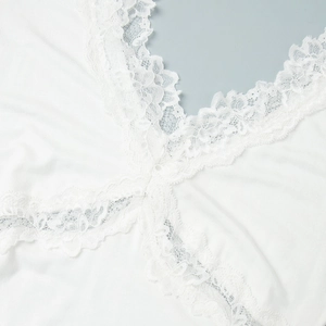 Détail de la bordure en dentelle délicate et du satin blanc sur un col en V