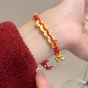 Detail of red woven bracelet with gold lucky coins and Pixiu pendant on wrist