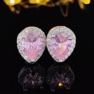 Detailed view of pink pear-shaped stud earrings with halo setting on reflective black surface
