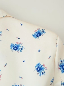 Macro shot of off-white woven fabric featuring blue and pink floral print details